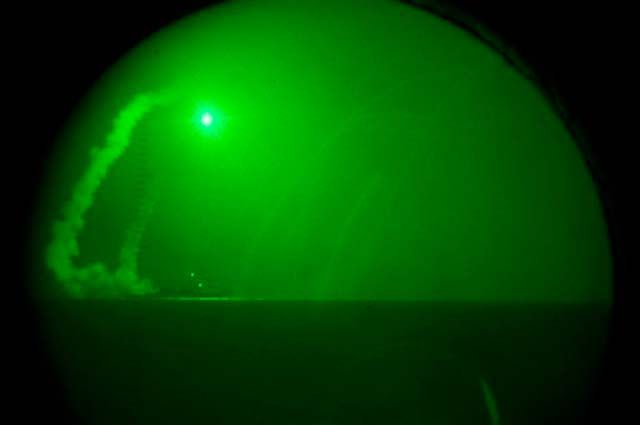 A  Saturday, March 19, 2011 photo provided by the U.S. Navy, seen through night-vision lenses aboard amphibious transport dock USS Ponce (LPD 15), the guided missile destroyer USS Barry (DDG 52) fires Tomahawk cruise missiles in support of Operation Odyssey Dawn from the Mediterranean Sea